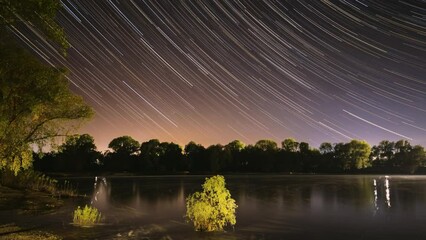 Wall Mural - Star Trails On Night Sky Background. 4k Timelapse Night Sky Above River. Star Lines Move In Sky. Amazing Starry Effects. From Dusk To Dawn. Night Sky Turns Into Morning. Dawn Is Coming. Time Lapse