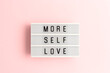 More self love. White lightbox with letters on a pink background.