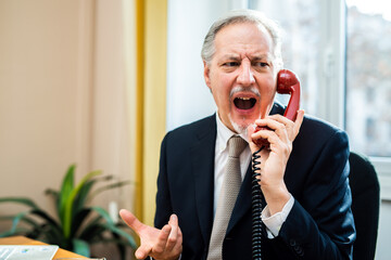 Wall Mural - Angry senior businessman yelling at the phone