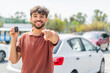 © luismolinero - Young Arabian handsome man holding car key at outdoors points finger at you with a confident expression