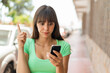 © luismolinero - Young woman at outdoors using mobile phone and lifting finger