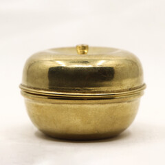 a traditional golden brass box bowl with lid used to store food spice and powder isolated in a white background in closeup