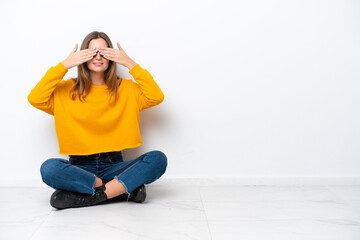 Wall Mural - Young caucasian woman sitting on the floor isolated on white background covering eyes by hands