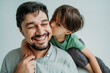 © Westend61 - Son kissing happy father on cheeks against white background