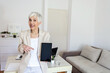 © Jelena Stanojkovic - Shot of a mature beautiful businesswoman holding up a digital tablet with a white screen. Businesswoman with digital tablet in home office.
