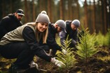 Fototapeta  - Volunteering. Young people volunteers outdoors reforestation. Man and woman planting trees in the forest or working in community garden.