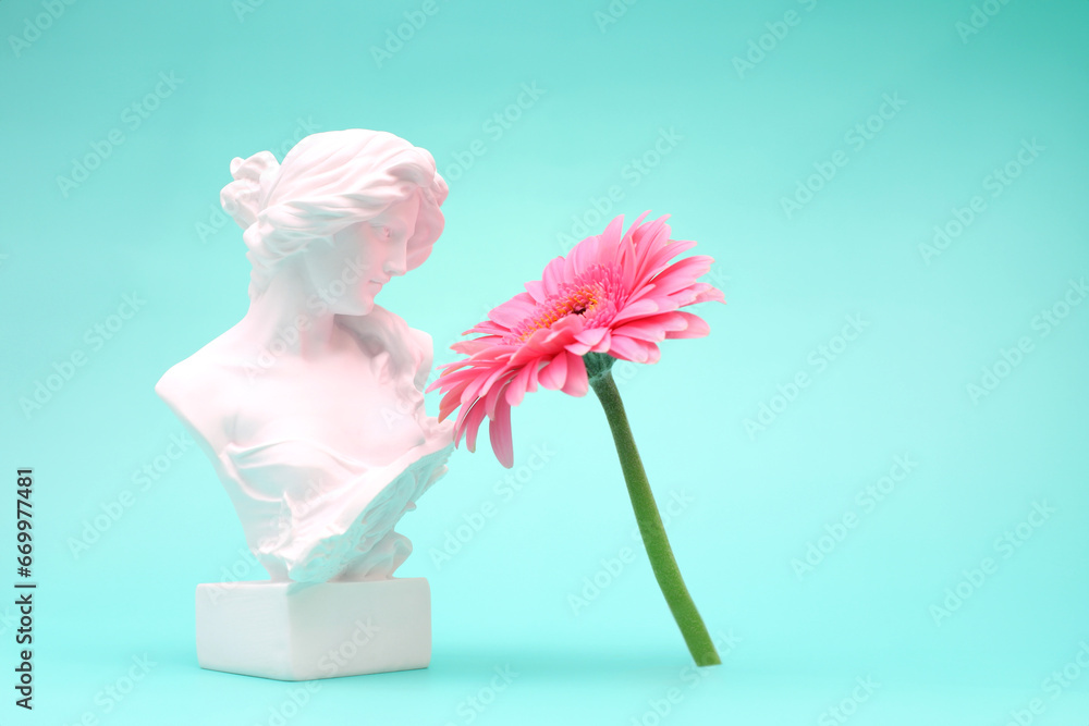 Female bust sculpure greek style with gerbera flower on blue background