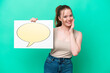 © luismolinero - Young caucasian woman isolated on green background holding a placard with speech bubble icon and shouting