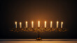 © puhimec - Hanukkah golden menorah with burning candles on a dark background.