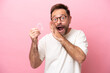 Middle age man holding invisible braces isolated on pink background whispering something