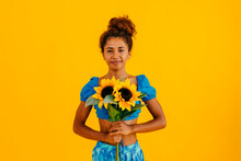Smiling Young Woman Holding Sunflowers Standing Against Yellow Background