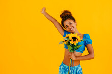 Happy Woman With Hand Raised Holding Sunflower Against Yellow Background