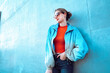 © VISTA by Westend61 - Woman wearing jacket leaning on blue wall