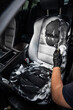 Man cleaning black leather car seat with brush and cleaning foam. 