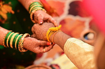 Wall Mural - Indian groom Tie a Turmeric Thread on hand of bride. Hands of bride and Groom in hindu wedding. Marathi Wedding Ceremony. Maharashtra Culture. Hindu wedding rituals and ceremony. Yellow knot