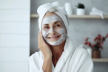 A Beautiful Elderly Gray-haired Woman With A Cosmetic Nourishing Moisturizing Mask On Her Face Smiles On Gray Background. Facial Skin Care Concept, Beauty, Care, Cosmetology
