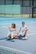 © bodnarphoto - Two stylish beautiful women tennis players in light clothes sitting on the court and resting after training, looking away