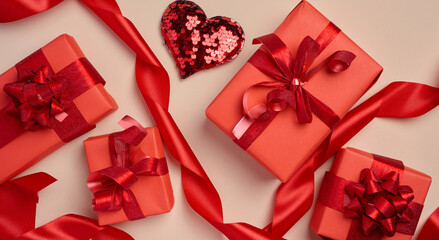 Wall Mural - Boxes packed in red paper and tied with ribbon on a beige background, gifts