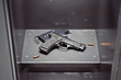 Handgun and stun gun on the shelf in a metal grey locker at school hallway.