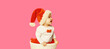 Happy smiling little child in christmas santa red hat playing with toys looking away on blank copy space for advertising text on pink studio background