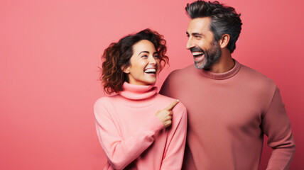 Against a pink background, a young woman and a man smile at each other, symbolizing a happy and close partnership.