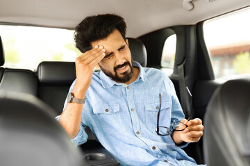 Wall Mural - Exhausted, overloaded man closing eyes with hand, experiencing headache