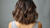 Elegant brunette hair cascading in soft waves, highlighting rich shades of brown and caramel against a muted background