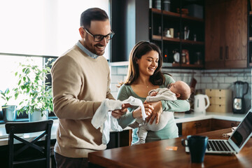 Wall Mural - Online shopping. Young family with infant child purchasing things on internet together.