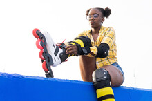 Woman Wearing Roller Skate Shoe On Blue Wall Against Clear Sky