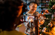 © Marko Geber - Young woman taking pictures of her lesbian partner decorating a Christmas tree at home