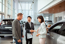Couple Finalizing A Car Purchase With A Dealership Representative