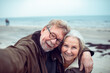 © Marko Geber - Happy senior couple taking a selfie at the beach during winter