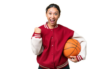 Wall Mural - Young Uruguayan woman playing basketball over isolated wall  over isolated chroma key background celebrating a victory in winner position