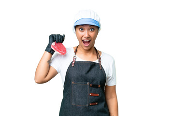 Wall Mural - Butcher woman wearing an apron and serving fresh cut meat over isolated chroma key background with surprise facial expression