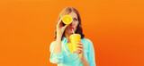 Summer portrait of happy young woman drinking fresh juice with slice of orange fruits and looking away on background