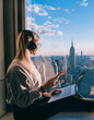 © BullRun - Hipster girl traveler enjoying panoramic view of New York downtown and studying with audio book