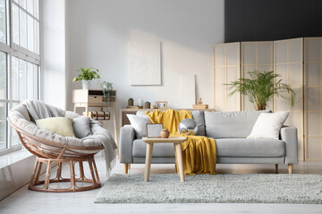 Interior of modern living room with disco ball on grey sofa, armchair and coffee table