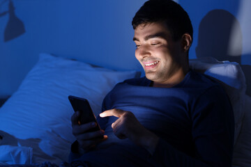 Poster - Young man using mobile phone in bed at night