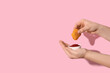 Woman holding tasty nugget and bowl of ketchup on pink background