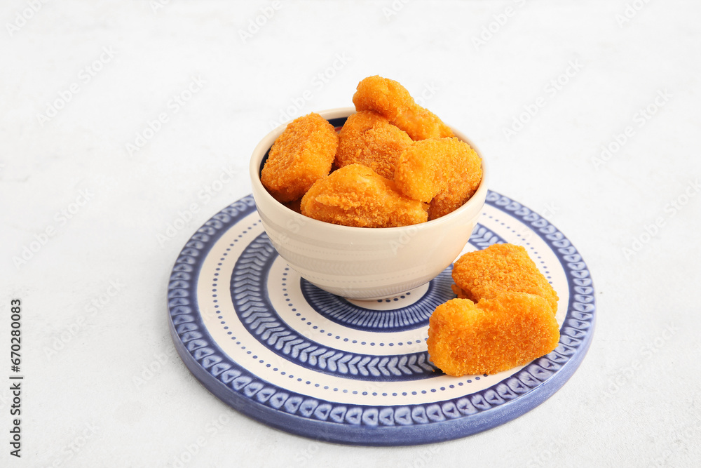 Bowl with tasty nuggets on white background