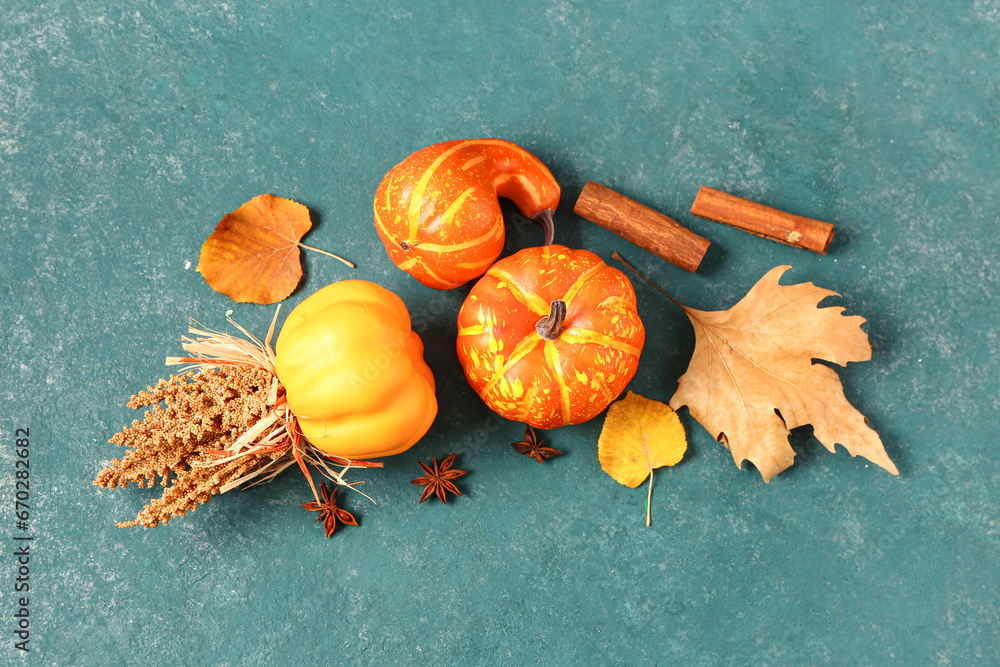 Autumn composition with ripe pumpkins, spices and fallen leaves on blue background
