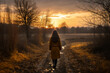 A young caucasian woman is walking happily with an autumn coat in a country landscape during sunset in autumn with no leaves on the trees