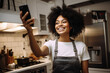 A young african american woman is is making a selfie while smiling with a telephone in a kitchen while cooking a high tech social media woman
