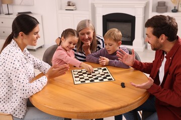 Canvas Print - Family playing checkers at wooden table in room