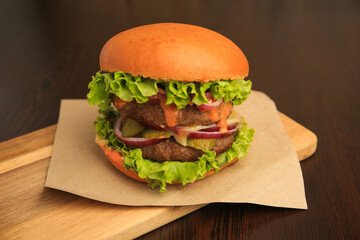 Wall Mural - Board with tasty burger on wooden table, closeup