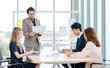 © Bangkok Click Studio - Asian professional successful male and female businessman businesswoman partnership colleagues in formal business suit sitting standing listening to presenter in meeting room in company office
