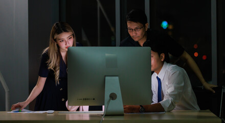 Asian professional skilled male programmer helping  computer problems for businesswoman employee working night shift overtime with male female businessman colleagues in office.