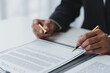 © Phimwilai - Businessman holding a pen to sign a contract, making a detailed agreement, business contract for finance, real estate, insurance, taxes and signing an official document.