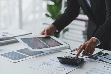 Wall Mural - Asian businesswoman works on laptop and calculates with financial calculator from graphs, statistics, charts. Planning. Business success results in modern office.