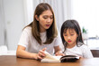 © Art_Photo - Portrait happy love asian family mother teach little daughter asian girl learn and study on table.Mom and asian young girl read book making lessons in homeschool at home.Education